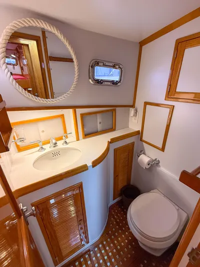 Argonaut Yacht Photos Pics Compact 1984 Wilbur 38 boat bathroom with wooden accents, round mirror, and porthole window.