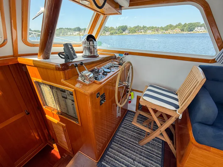 Argonaut Yacht Photos Pics Helm of 1984 Wilbur 38 boat with wooden steering wheel and striped chair.