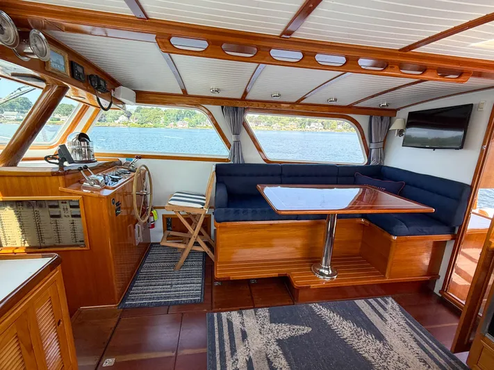 Argonaut Yacht Photos Pics Interior of 1984 Wilbur 38 boat with wooden finish, blue seating, and steering wheel.