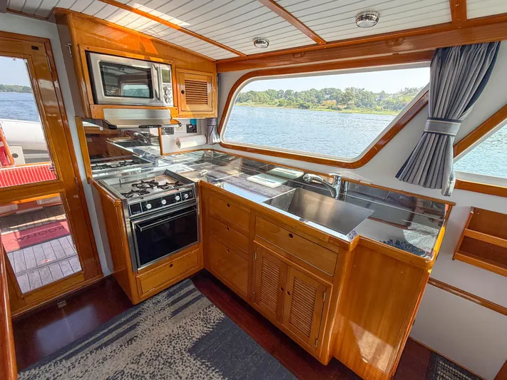 Argonaut Yacht Photos Pics Kitchen area of a 1984 Wilbur 38 boat with wooden cabinetry and scenic water view.