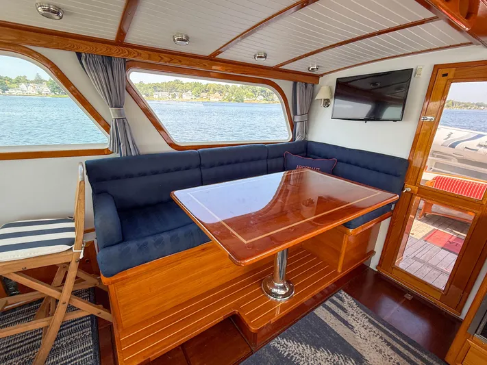Argonaut Yacht Photos Pics Interior of 1984 Wilbur 38 boat with wooden table, blue seating, and waterfront view.