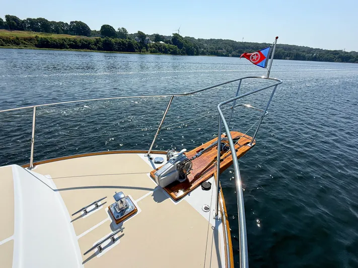 Argonaut Yacht Photos Pics Bow of 1984 Wilbur 38 boat with flag, cruising on a calm lake.