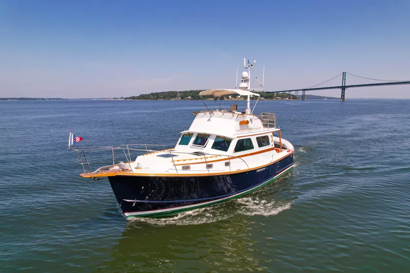 Argonaut Yacht Photos Pics 1984 Wilbur 38 yacht cruising near a bridge on a sunny day.