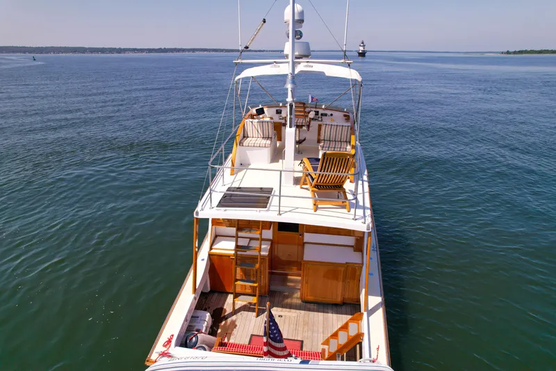 Argonaut Yacht Photos Pics 1984 Wilbur 38 yacht on calm water, featuring wooden deck chairs and American flag.