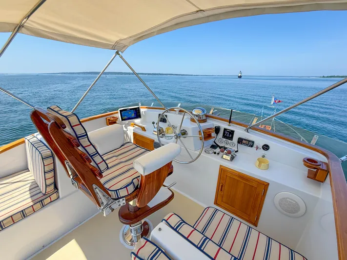 Argonaut Yacht Photos Pics Helm of 1984 Wilbur 38 boat with striped seating, overlooking calm blue waters.