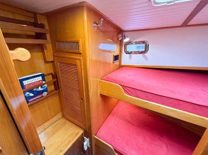 Argonaut Yacht Photos Pics Cozy cabin interior of 1984 Wilbur 38 with red bunk beds and wooden shelving.