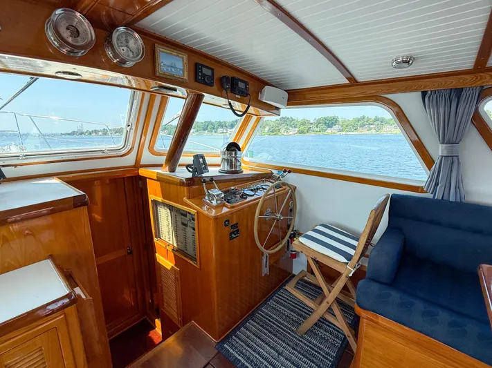 Argonaut Yacht Photos Pics Interior of 1984 Wilbur 38 boat with wooden helm, striped chair, and scenic water view.