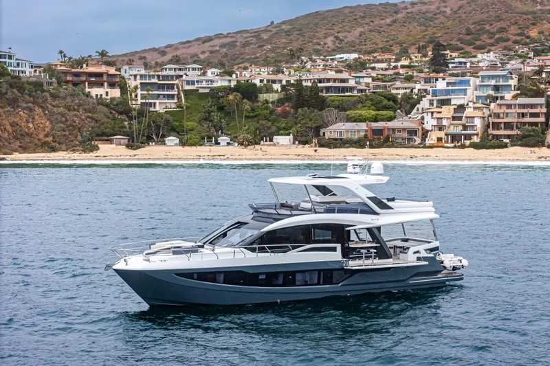  Yacht Photos Pics 2023 Galeon 640 Fly yacht cruising near scenic coastal homes.