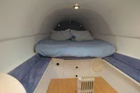 Compact sleeping area inside a 2007 Custom VSV, featuring a cozy bed and minimalist design.