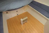 Small heater on wooden floor in cozy room with blue bedding, Custom VSV 2007 model.