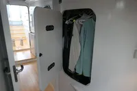Compact closet with hanging clothes inside a 2007 Custom VSV boat interior.