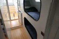 Compact cabin interior with bunk beds, wooden flooring, and a small fridge in a 2007 Custom VSV.