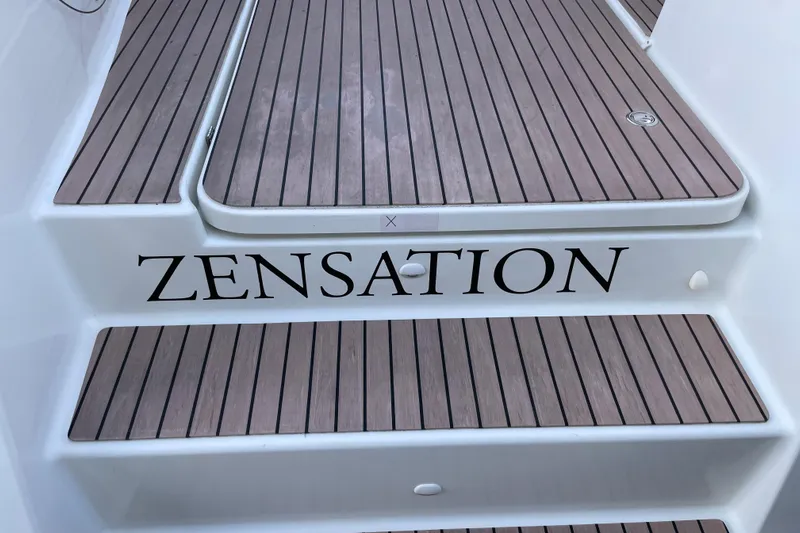 Zensation Yacht Photos Pics 2023 Fountaine Pajot Tanna 47 yacht with "Zensation" on wooden deck steps.