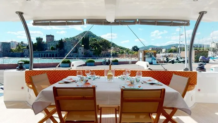 Ti Marin Yacht Photos Pics Dining setup on 2020 O Yachts Class 6, overlooking scenic marina and mountains.