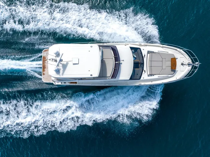  Yacht Photos Pics Aerial view of 2020 Prestige 590 Flybridge Cruiser navigating through blue ocean waters.