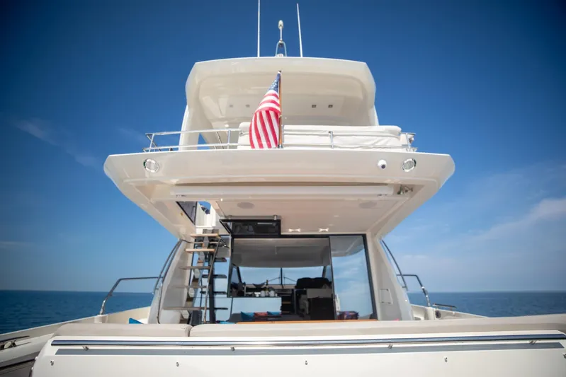  Yacht Photos Pics 2020 Prestige 590 Flybridge Cruiser on open sea, rear view with American flag.