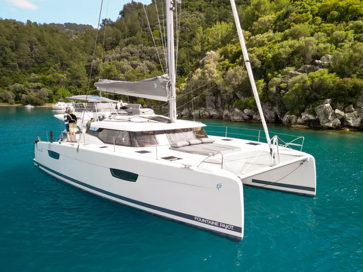  Yacht Photos Pics 2023 Fountaine Pajot Tanna 47 catamaran sailing in clear turquoise waters.
