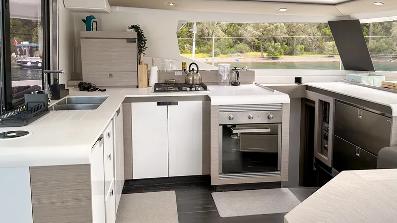  Yacht Photos Pics Modern kitchen interior of 2023 Fountaine Pajot Tanna 47 catamaran, featuring sleek appliances and ample counter space.