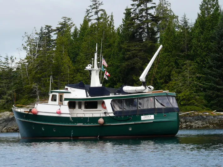 Orina Yacht Photos Pics 1971 Southern Marine MALAHIDE Pilothouse LRC boat on calm water, surrounded by lush trees.