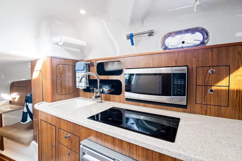 Let&rsquo;s Go II Yacht Photos Pics 2013 Pursuit OS 345 Offshore yacht kitchen with wood cabinetry, microwave, and stovetop.