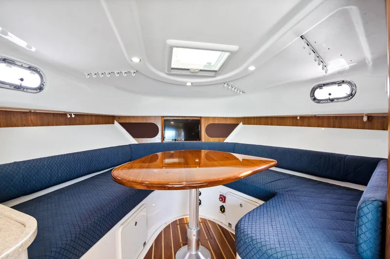 Let&rsquo;s Go II Yacht Photos Pics 2013 Pursuit OS 345 Offshore cabin interior with blue seating and wooden table.