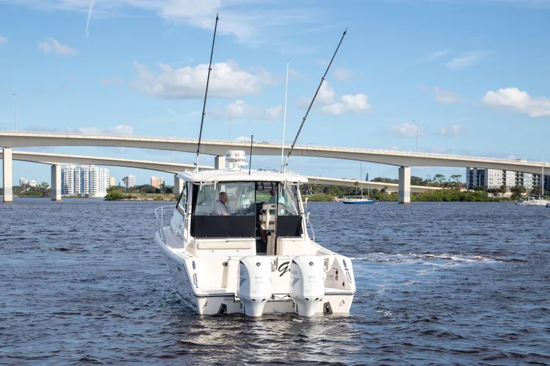 Let&rsquo;s Go II Yacht Photos Pics 2013 Pursuit OS 345 Offshore boat cruising under a bridge on a sunny day.