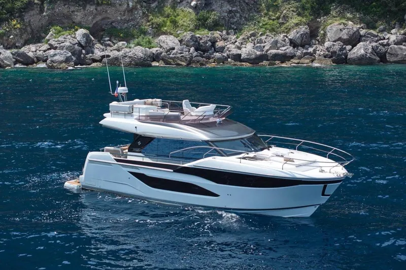  Yacht Photos Pics Luxurious 2026 Prestige F4.9 yacht cruising in clear blue waters near rocky shoreline.