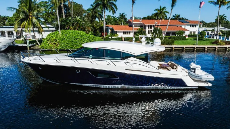 Happy Daze IV Yacht Photos Pics 2017 Tiara Yachts 53 Coupe cruising on a serene waterway, surrounded by lush greenery.