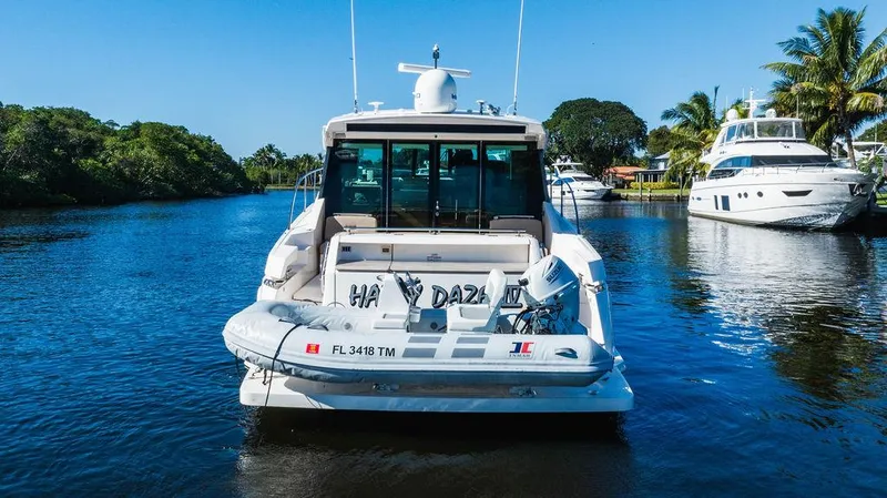 Happy Daze IV Yacht Photos Pics 2017 Tiara Yachts 53 Coupe on a serene waterway, surrounded by lush greenery and other boats.