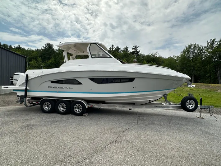  Yacht Photos Pics 2019 Regal 33 SAV boat on trailer, parked outdoors under cloudy sky.