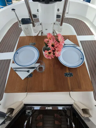 Momentum Yacht Photos Pics Dining setup on 2007 Hunter 45 Center Cockpit yacht with flowers and plates.