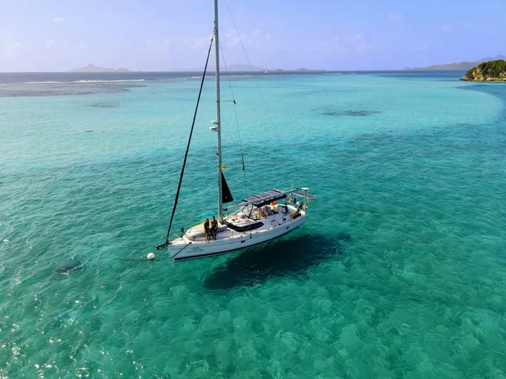 Momentum Yacht Photos Pics Sailboat "Hunter 45 Center Cockpit" 2007 on turquoise sea, clear skies, distant islands.