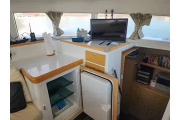 Buzio Yacht Photos Pics Interior of 2014 Lagoon 380 S2 catamaran with fridge, TV, and storage shelves.