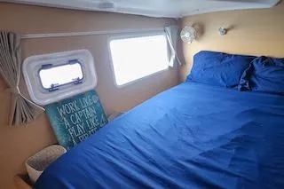 Buzio Yacht Photos Pics Cozy cabin interior of 2014 Lagoon 380 S2 with blue bedding and nautical decor.