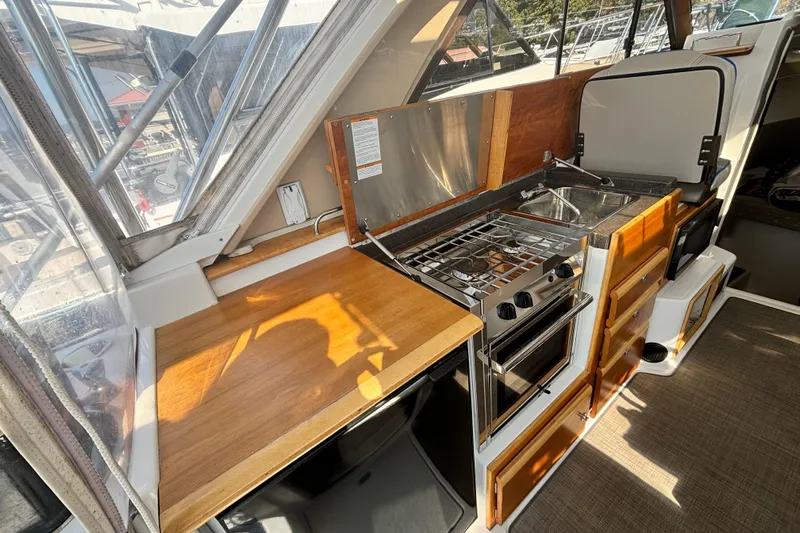  Yacht Photos Pics 2017 Cutwater C-302 Sport Coupe interior kitchen with stove, sink, and wooden cabinetry.