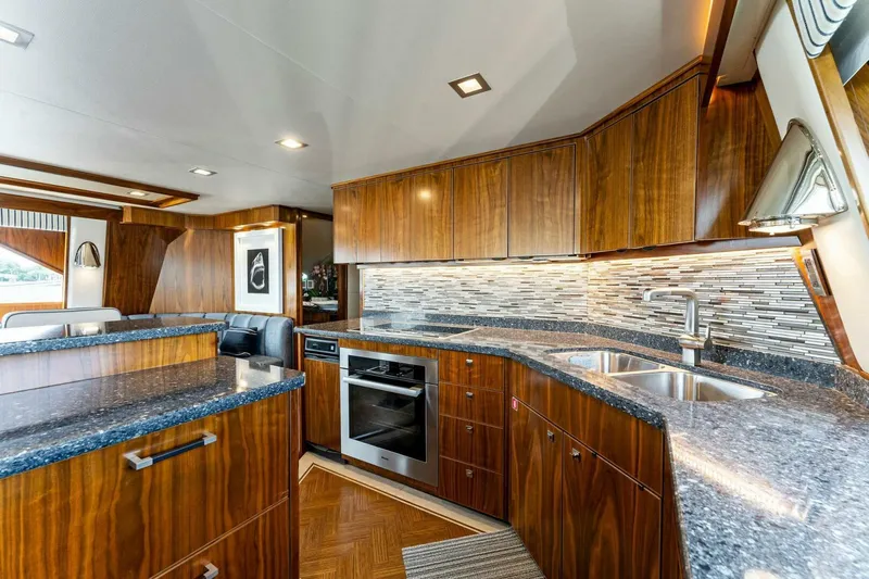 Aussie Rules Yacht Photos Pics Luxurious kitchen interior of 2017 Viking 92 Enclosed Bridge yacht with wood cabinetry and modern appliances.