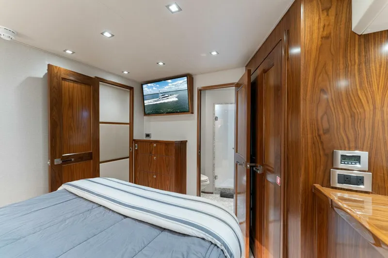 Aussie Rules Yacht Photos Pics Luxurious bedroom interior of 2017 Viking 92 Enclosed Bridge yacht with wood paneling.