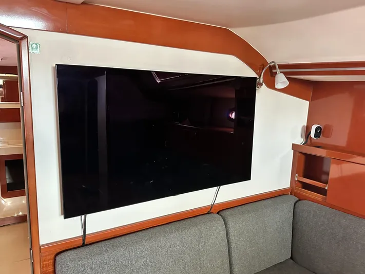 Blue Yacht Photos Pics Interior of 2006 Hanse 461 yacht with mounted TV and gray sofa.