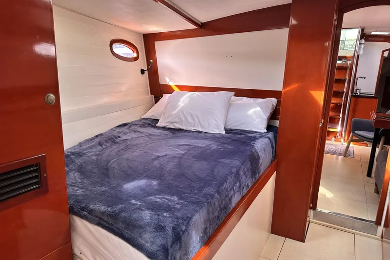 Blue Yacht Photos Pics Cozy cabin interior of 2006 Hanse 461 yacht with plush bedding and wooden accents.