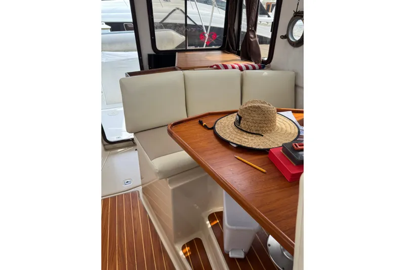 Lady Mary Yacht Photos Pics Interior of 2009 Ranger Tugs R-29 with wooden table, straw hat, and cushioned seating.