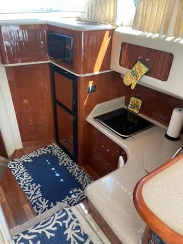  Yacht Photos Pics 2003 Sea Ray 400 Sedan Bridge kitchen with wood cabinetry, stove, and microwave.