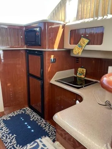  Yacht Photos Pics 2003 Sea Ray 400 Sedan Bridge kitchen with microwave, stove, and wooden cabinetry.