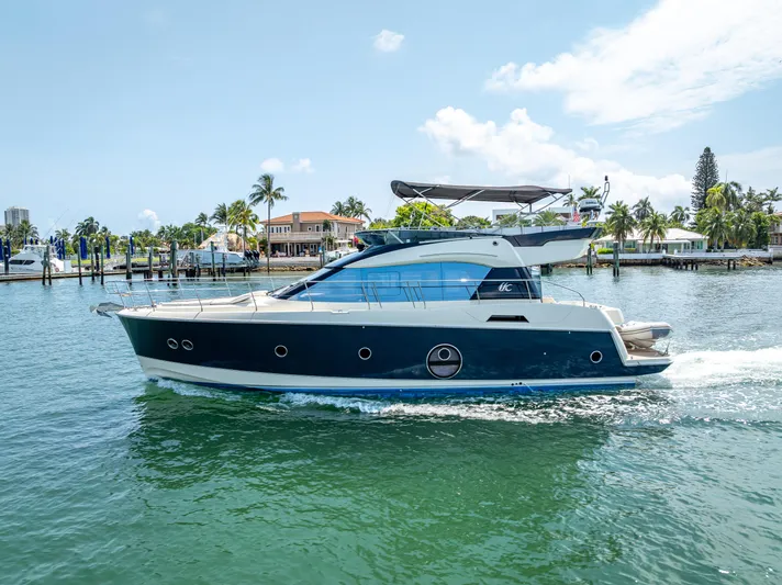 Good Deeds Yacht Photos Pics 2015 Beneteau Monte Carlo 5 yacht cruising on a sunny day near a tropical shoreline.