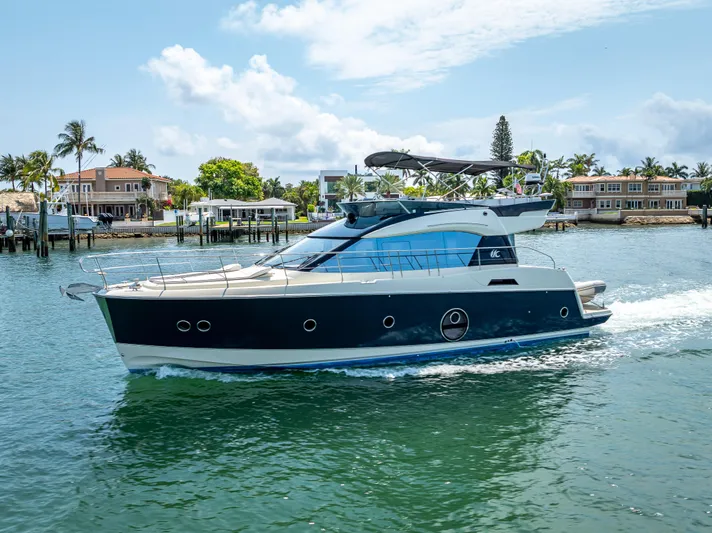 Good Deeds Yacht Photos Pics 2015 Beneteau Monte Carlo 5 yacht cruising on a sunny day near waterfront homes.