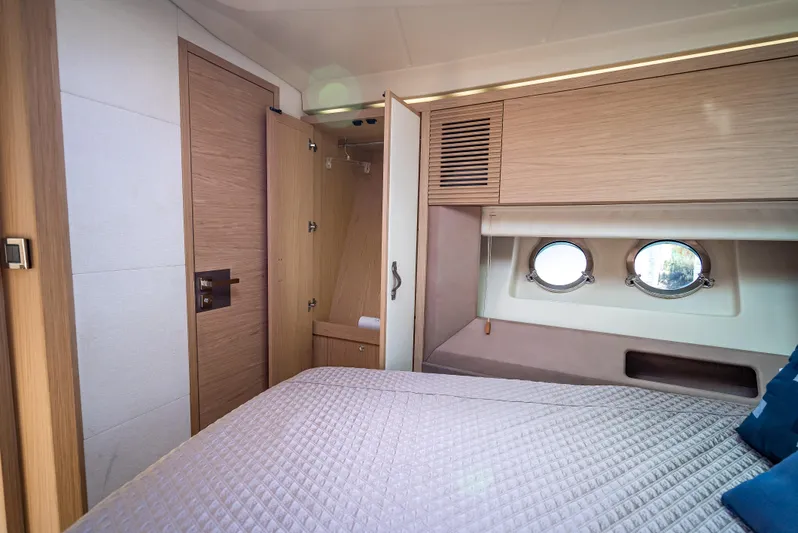 Good Deeds Yacht Photos Pics 2015 Beneteau Monte Carlo 5 cabin interior with bed, portholes, and wooden cabinetry.