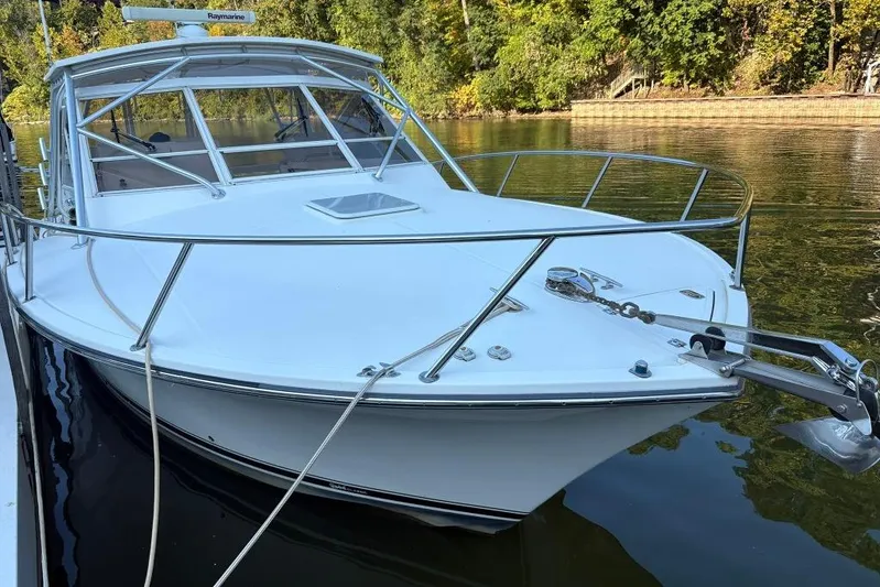 Yacht Photos Pics 2006 Carolina Classic 32 boat docked on calm water, surrounded by lush greenery.