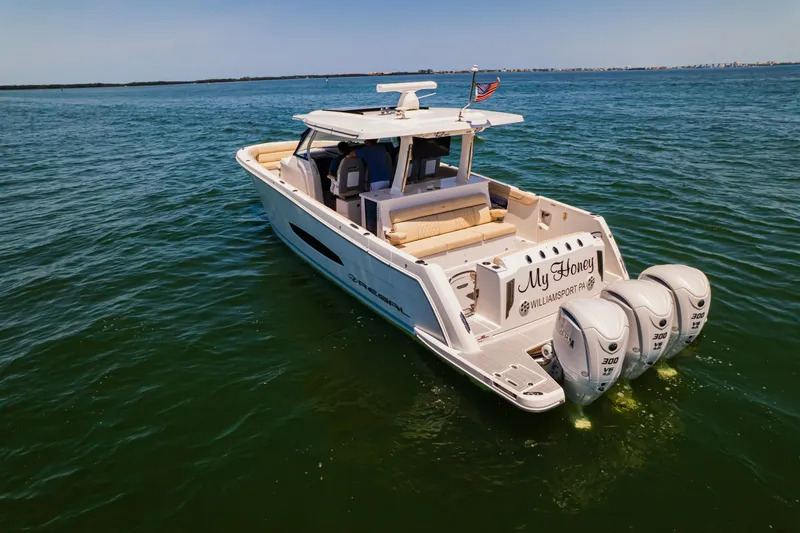 My Honey Yacht Photos Pics 2023 Regal 38 SAV boat cruising on open water with triple outboard engines.