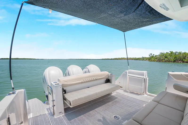 My Honey Yacht Photos Pics 2023 Regal 38 SAV boat with seating area and canopy on calm water.