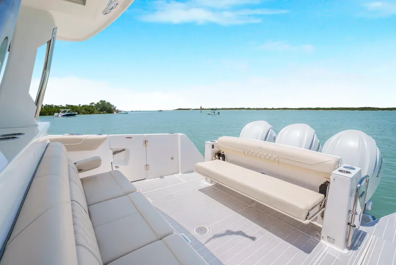 My Honey Yacht Photos Pics 2023 Regal 38 SAV boat interior with seating, overlooking serene water and clear sky.
