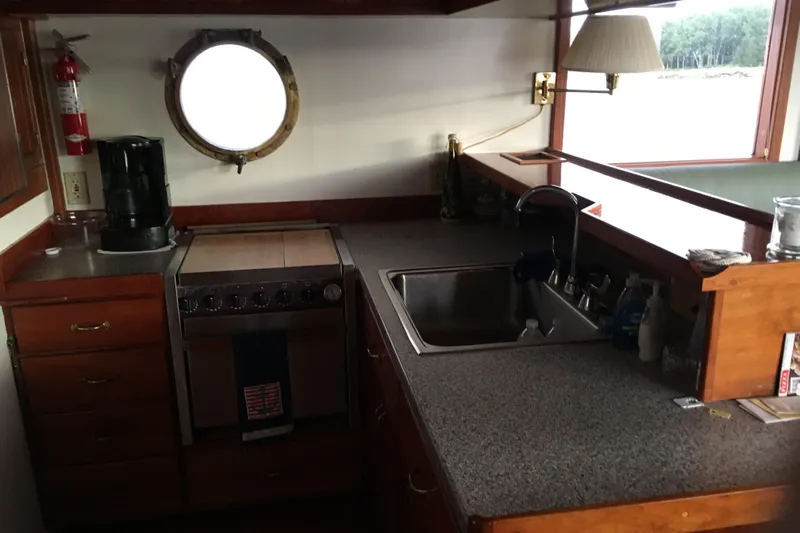  Yacht Photos Pics Cozy kitchen area on 1999 Custom Jack Gilbert 50 Trawler with sink, stove, and porthole window.